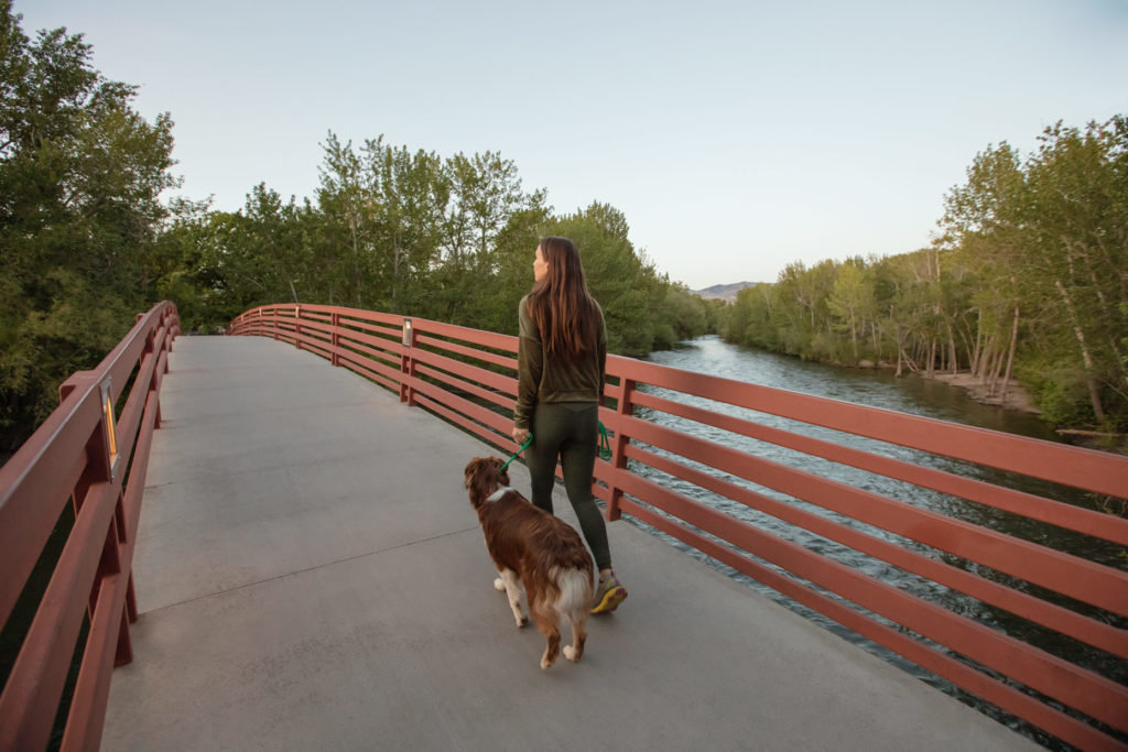 Young lady walking a dog across a quaint bridge